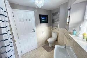 a bathroom with a toilet and a white door at A charming cottage set in Bridgetown Totnes. in Dean