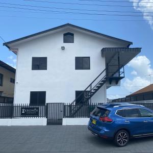 um carro azul estacionado em frente a uma casa branca em HHC Apartments Kronos em Paramaribo