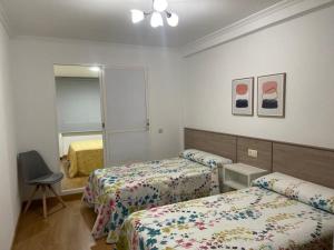 een hotelkamer met 2 bedden en een spiegel bij Piso O cruceiro in O Grove