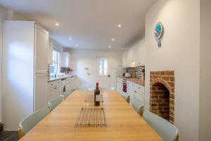 una cucina con un lungo tavolo e una bottiglia di vino di Large pretty holiday cottage by the sea sleeps 10 a Heacham