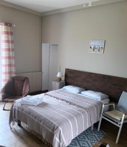 a bedroom with a large bed and a chair at La Costonnerie in Leigné-sur-Usseau