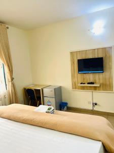 um quarto de hotel com uma cama e uma televisão na parede em OD-V!CK'S LUXE, Wuse Zone 4, Swimming Pool, Gym, WiFi, 24hr power, security, Dstv em Abuja