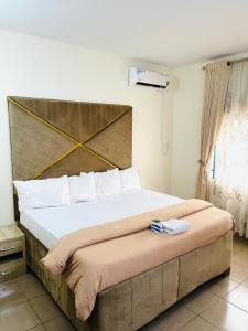 um quarto com uma cama grande e uma cabeceira em madeira em OD-V!CK'S LUXE, Wuse Zone 4, Swimming Pool, Gym, WiFi, 24hr power, security, Dstv em Abuja