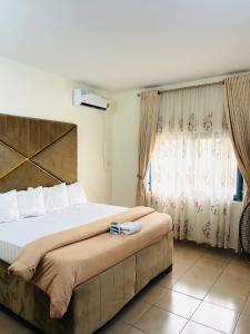 um quarto com uma cama grande e uma janela em OD-V!CK'S LUXE, Wuse Zone 4, Swimming Pool, Gym, WiFi, 24hr power, security, Dstv em Abuja