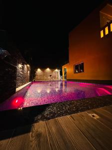 a swimming pool lit up at night with purple lights at The Orchard House in Raichak