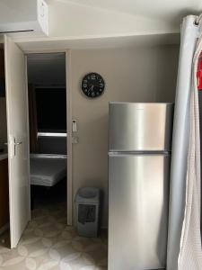 a kitchen with a refrigerator and a clock on the wall at Mobil home Aventura 6-8 personnes tout confort in Saint-Brevin-les-Pins
