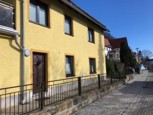 una casa amarilla con una valla al lado de una calle en FeWo Kästner Pirna, en Pirna