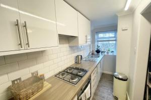 a kitchen with white cabinets and a stove top oven at Torquay in Torquay