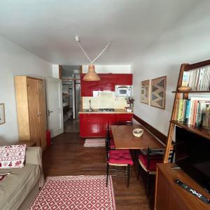 a living room with a table and a kitchen with red cabinets at appartamento Cervinia fronte Funivie in Breuil-Cervinia