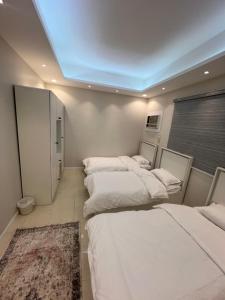 uma fila de quatro camas num quarto em شقة مخدومه مفروشة قباء 303 em Medina