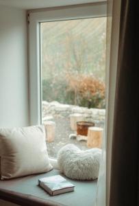 una ventana con una almohada y un libro en un alféizar de la ventana en Somló Nordic, en Somlószőlős