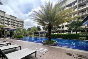uma piscina com uma palmeira em frente a um prédio em 3BR Resort Style Condo em Manilla