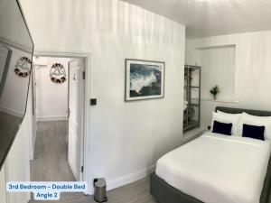 een witte slaapkamer met een bed en een hal bij OCEAN ESCAPE 200m From the Sea, High Spec Town Centre Entire Flat, 3 Bedrooms, TVs All Rooms in Porthcawl