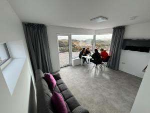 ein Wohnzimmer mit einem Sofa und Menschen am Tisch in der Unterkunft Coastal Escape in Burtonport