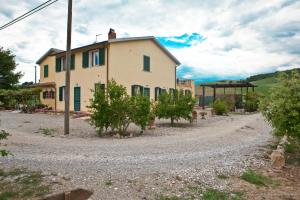 a house on a gravel road with trees in front at La Nostra Maremma in Marsiliana