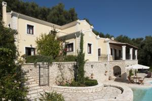 a large house with a stone wall next to a pool at Villa Maro in Ágios Stéfanos