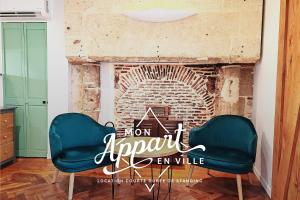 two chairs in front of a brick fireplace with a mom apart sign at L' échafaud - Apparts de standing - Centre historique in Périgueux