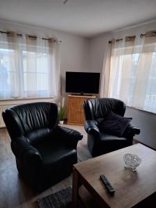 a living room with two leather chairs and a television at Emma in Greifswald