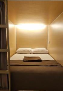 una cama con una luz encima en Fora Capsule Hostel Tuban Kuta Bali, en Kuta