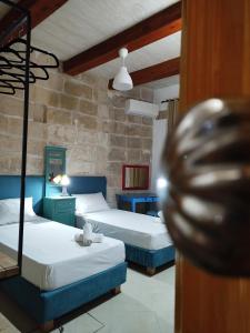 a bedroom with two beds and a stone wall at Limestone Sun Suites in Sliema