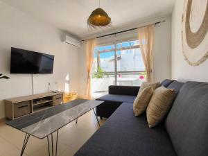 ein Wohnzimmer mit einem blauen Sofa und einem TV in der Unterkunft Medina Marinas - Tú hogar con solarium privado! in Vera