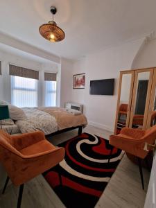 um quarto com uma cama e 2 cadeiras e uma televisão em Alton Rd guesthouse em Liverpool