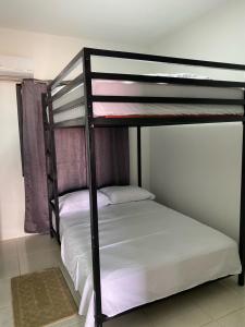 two bunk beds in a room with white sheets at KRONOS APARTMENTS in Paramaribo