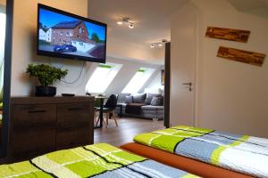 1 dormitorio con TV en la pared y 1 cama en Speedys Gästehaus am Brünnchen, en Herresbach