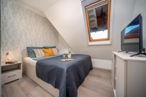 ein kleines Schlafzimmer mit einem Bett und einem Fernseher in der Unterkunft La Vida apartman Hajdúszoboszló in Hajdúszoboszló