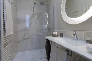 uma casa de banho com um chuveiro, um lavatório e um espelho. em Brera Prestige B&B em Milão