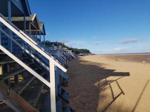 una spiaggia con un edificio blu e una spiaggia sabbiosa di Large pretty holiday cottage by the sea sleeps 10 a Heacham