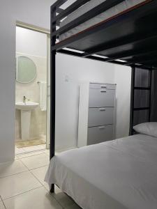 1 dormitorio con 1 cama y baño con lavamanos en KRONOS APARTMENTS en Paramaribo