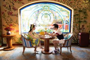 un hombre y una mujer sentados en una mesa en un restaurante en Venice Hotel Phu Quoc - Free Hon Thom Island Waterpark Cable Car & Sunset Town Tour en Phu Quoc