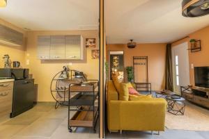 a living room with a yellow couch and a kitchen at Au Doux Refuge - Maison - Parking gratuit in Romorantin