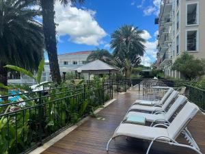 una fila di sedie a sdraio bianche su una terrazza di legno di Destino Floripa Jurerê In a Florianópolis