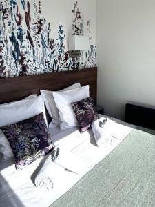 uma cama com almofadas com uma parede floral em Penthouse vue mer et jacuzzi privé em Antibes