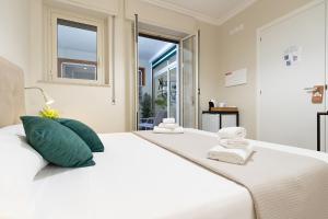 1 dormitorio blanco con 1 cama blanca grande con almohadas verdes en NeryHome Giardini Naxos, en Giardini Naxos