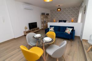 uma sala de estar com um sofá azul e cadeiras amarelas em Apartamentos La Escapada em Alhama de Aragón