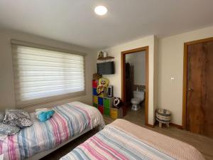 1 dormitorio con 2 camas y ventana en Casa de Campo Familiar Malchingui, en Papallacta