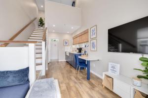 a living room with a staircase and a blue desk at SANDY - Cheerful 1 bedroom tiny house with pool in Dunedin
