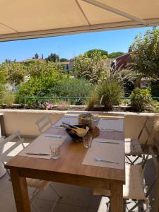 a wooden table on a patio with an umbrella at Apartment Port Grimaud in Grimaud