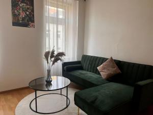 ウィーンにあるLuxus Apartmentのリビングルーム(緑のソファ、ガラスのテーブル付)