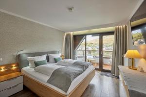 een slaapkamer met een groot bed en een balkon bij Mayer's Weinhotel in Zell an der Mosel