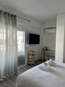 a white bedroom with a bed and a television at Vamelon in Athens