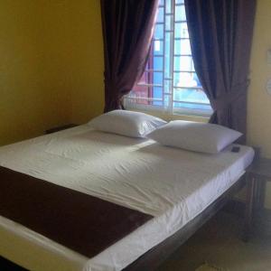 1 cama con sábanas y almohadas blancas frente a una ventana en The Hideout en Kampot