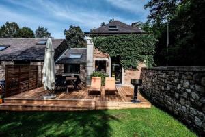 een houten terras met een parasol en een tafel en stoelen bij L'arche De Noé in Dinant