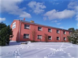 a red building with snow in front of it at Pension Stocker in Dierhagen