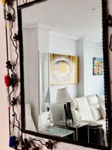San Pedro con ascensor y recogida في سانتا بولا: مرآة تعكس غرفة معيشة مع أريكة بيضاء