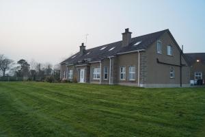 ein Haus mit einem großen Grasfeld davor in der Unterkunft Clonmurr B&B in Ballyroney