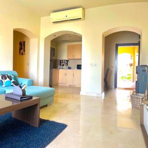 a living room with a blue couch and a kitchen at Azzura appartment sahl hashesh with private garden in Hurghada